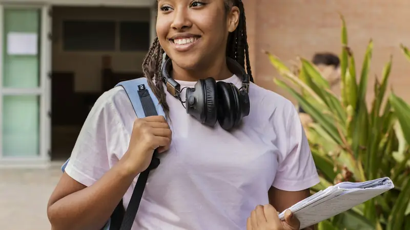 Estudiante sonriente con mochila y libros en el campus